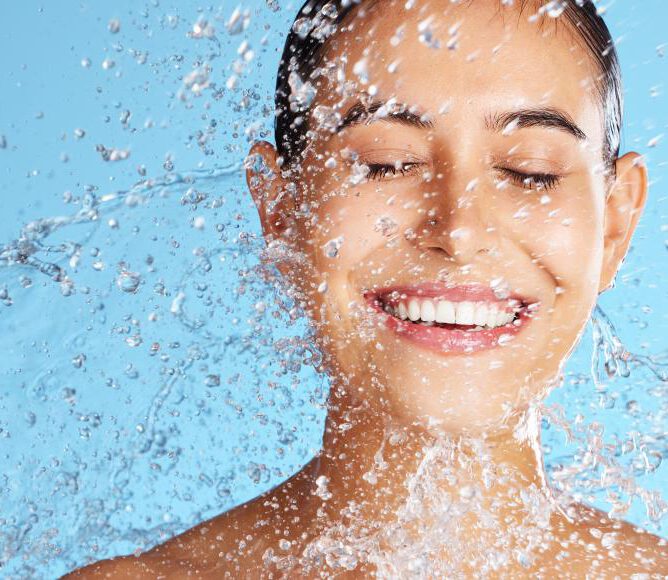Aqua facial Kosmetikbehandlung mit Feuchtigkeitsspende - fröhliche Frau mit Wasserspritzern im Gesicht